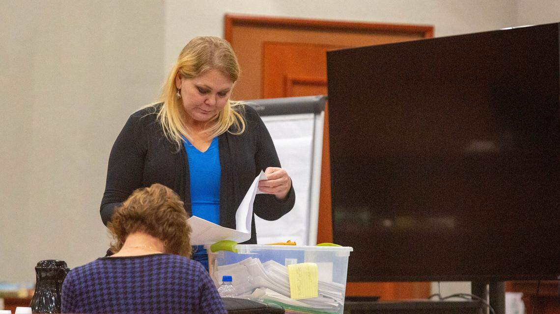 Tammy Moorer thumbs through files at the defense table Thursday afternoon during a break in court proceedings.