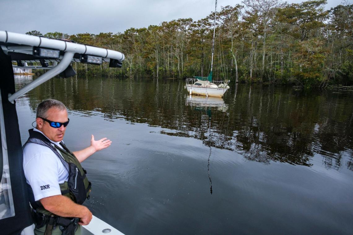 Captain Michael Paul Thomas of the South Carolina Department of Natural Resources points out an abandoned sailboat near Bucksport. Abandoned boats litter the waterways throughout Horry County, S.C. The Department of Natural Resources is partnering with non-profit conservation groups and local businesses to begin removing the derelict vessels from local waterways. Oct. 6, 2021.