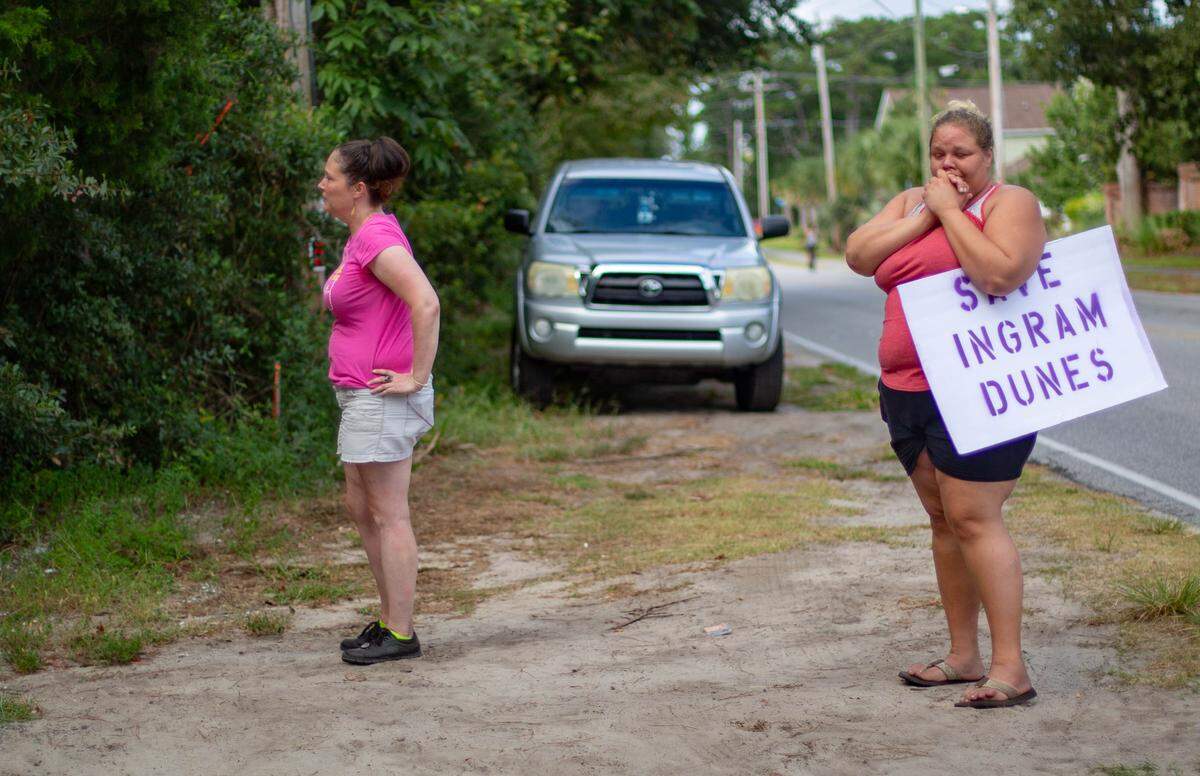 Protestors watch as crews work to clear Ingram Dunes on Monday in North Myrtle Beach.