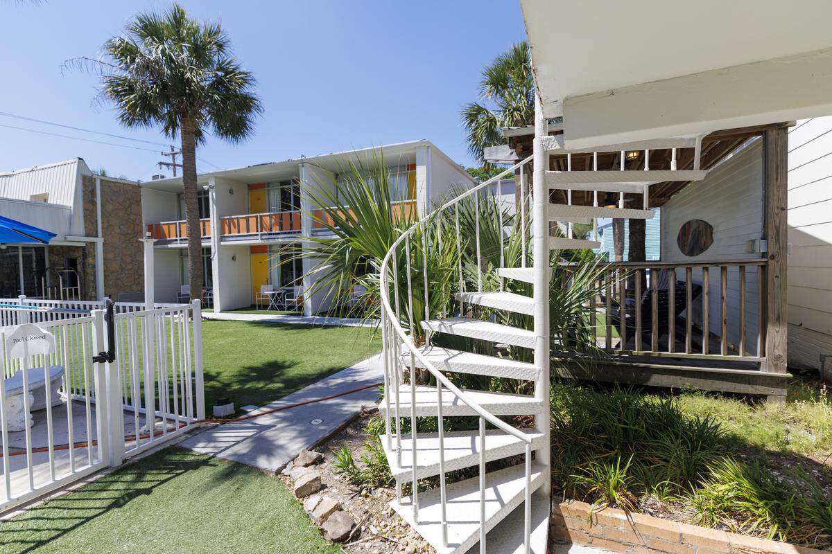The renovation of Holiday Shores leaned into this vintage look with updated rooms that has mid-century modern architecture, bright colors and geometric designs, as well as bistro tables, astroturf on the outside and balconies that overlook the popular swimming pool. The metal, spiral staircase was also kept as a nod to the 1960s look.