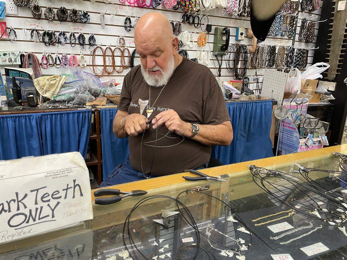 Tom Pierce, who operates Trader Bill Shark Teeth inside the Gay Dolphin in downtown Myrtle Beach, SC, works on a piece of jewelry using a shark’s tooth. Pierce has been making jewelry and selling shark teeth for 56 years.