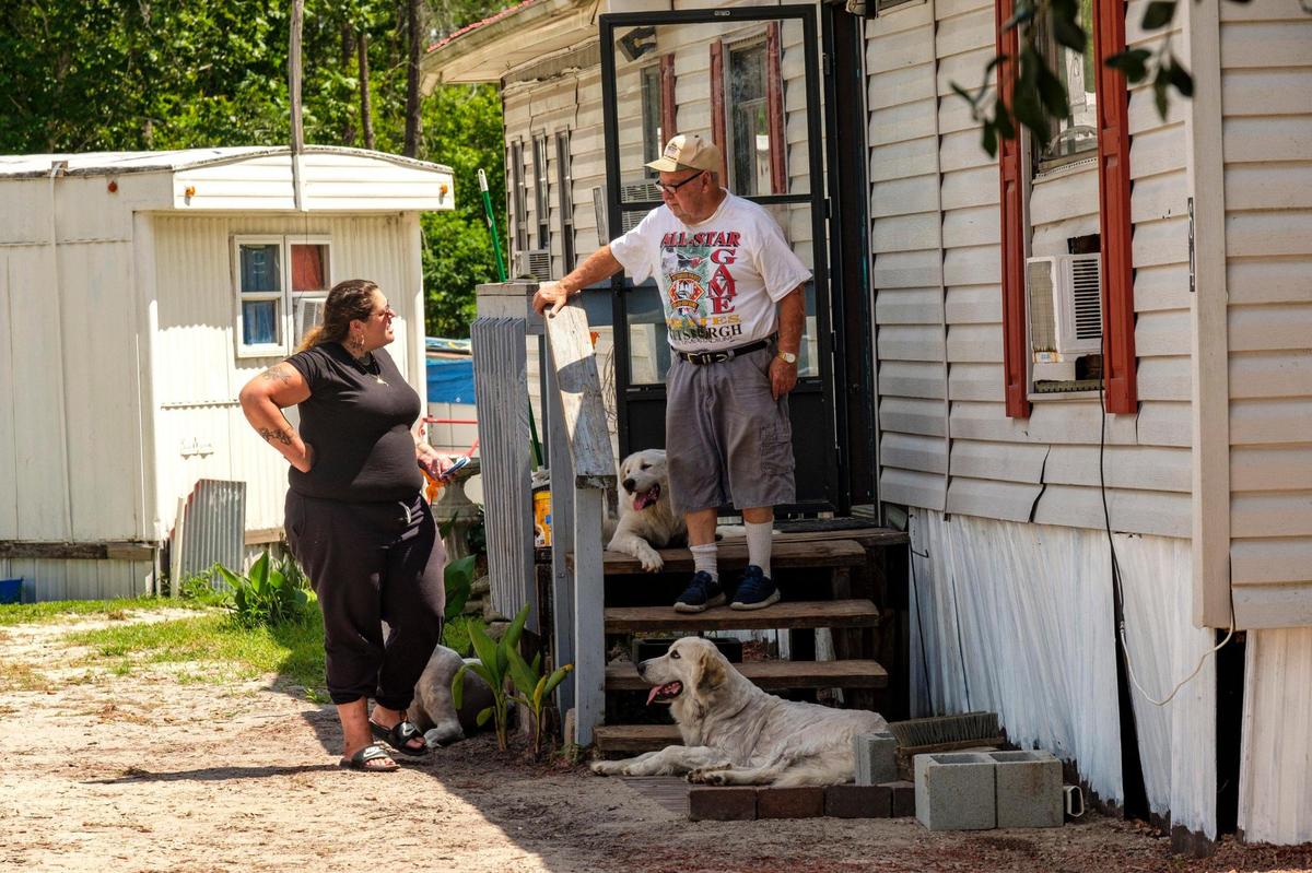 Residents visit on the porch home a mobile home at the Recovery Ranch, a living facility for those struggling with homelessness, mental illness and drug addictions. The facility has come under fire by county officials for code violations and the volume of 9-11 calls. According to the founder, the facility could be shut down leaving approximately 75 residents with no where to go. July 1, 2021.