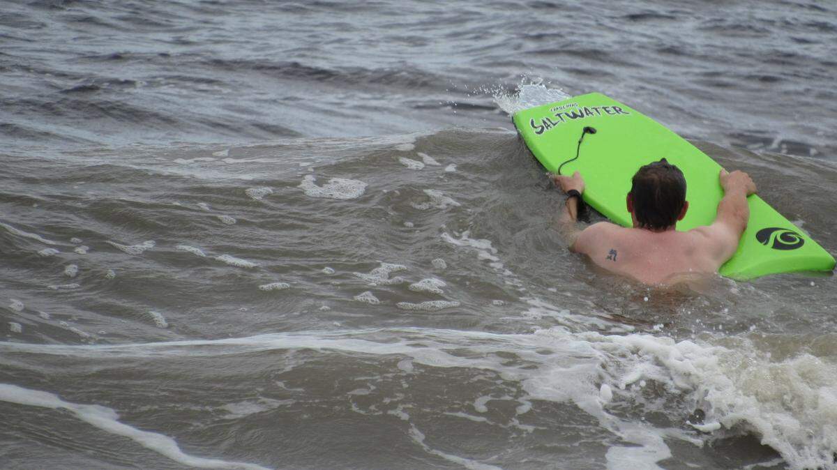 A man takes his boogie board Monday, Sept. 24 into the ocean at Myrtle Beach along the boardwalk. Myrtle Beach lifted its beach ban Sept. 18, but state officials are advising against entering the water due to potential contaminants and debris from Hurricane Florence.