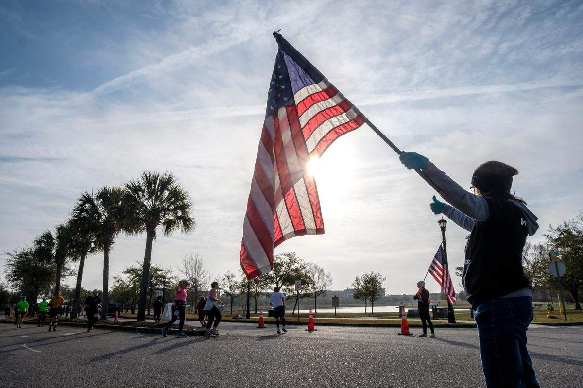 Volunteers wave flags that indicate the sharp turn around in Market Common during the 25th Myrtle Beach Marathon Saturday. Approximately 4.500 runners participating in the full marathon, half marathon and 5K races. March 05, 2022.