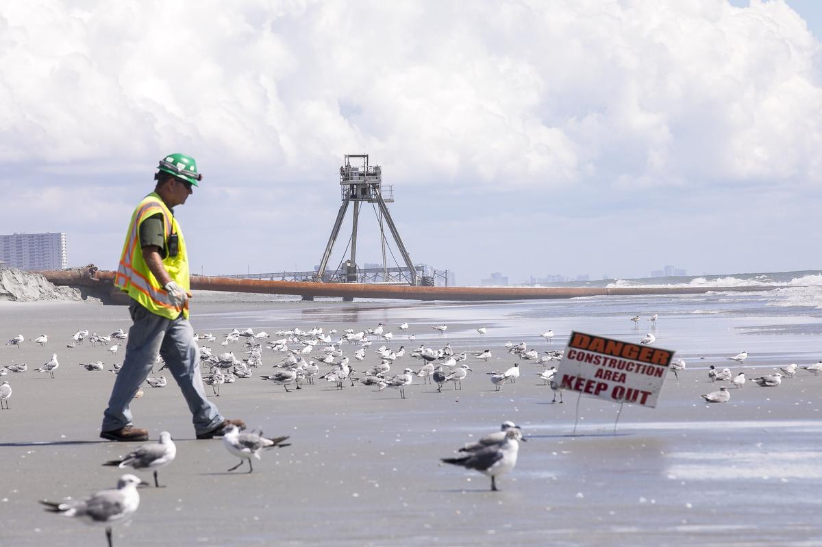A contractor with the United States Army Corps of Engineers guards the site of beach renourishment in Surfside Beach on Wednesday where a 30-foot-tall “crab” structure provides constant site surveys to assure that 1.4 million cubic yards of sand is distributed properly along Grand Strand beaches. September 5, 2018.