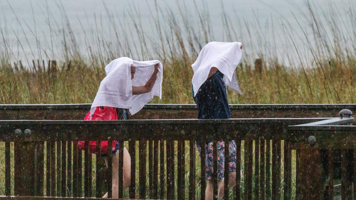Visitors look for cover from the rain as a storm hits downtown Myrtle Beach on Friday evening. Downtown Myrtle Beach’s tourist district was relatively quiet for a Summer evening on Ocean Boulevard and the Boardwalk. Storms put a damper on the evening activities but as the skies cleared, visitors returned to enjoy the attractions. Friday, May 30, 2025.