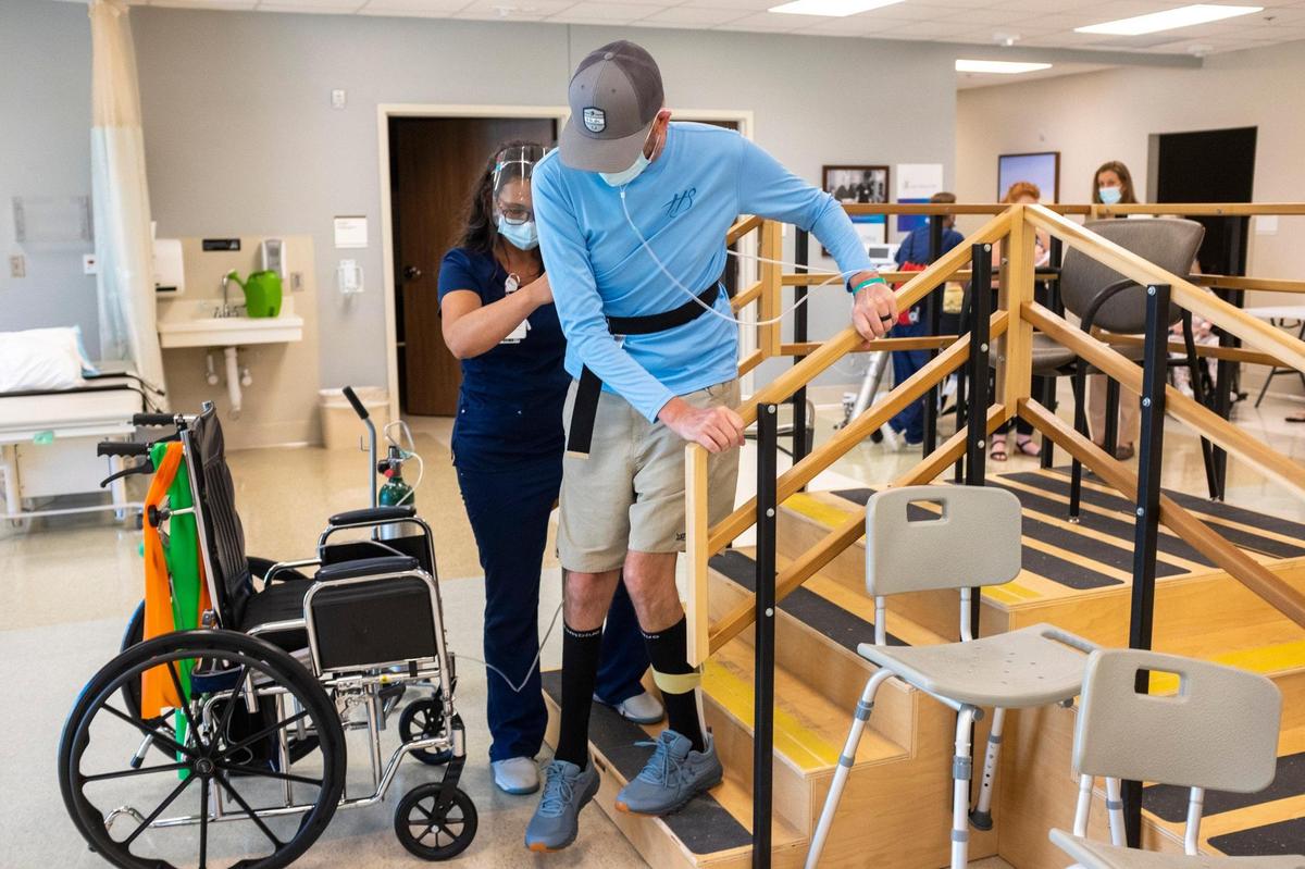 Chad Hardee practices walking up and down steps at Tidelands Health Rehabilitation Hospital at Little River with his Physical Therapy Assistant and neighbor Kristin Mills in hopes of being able to climb into his house under his own power . May 20, 2021.