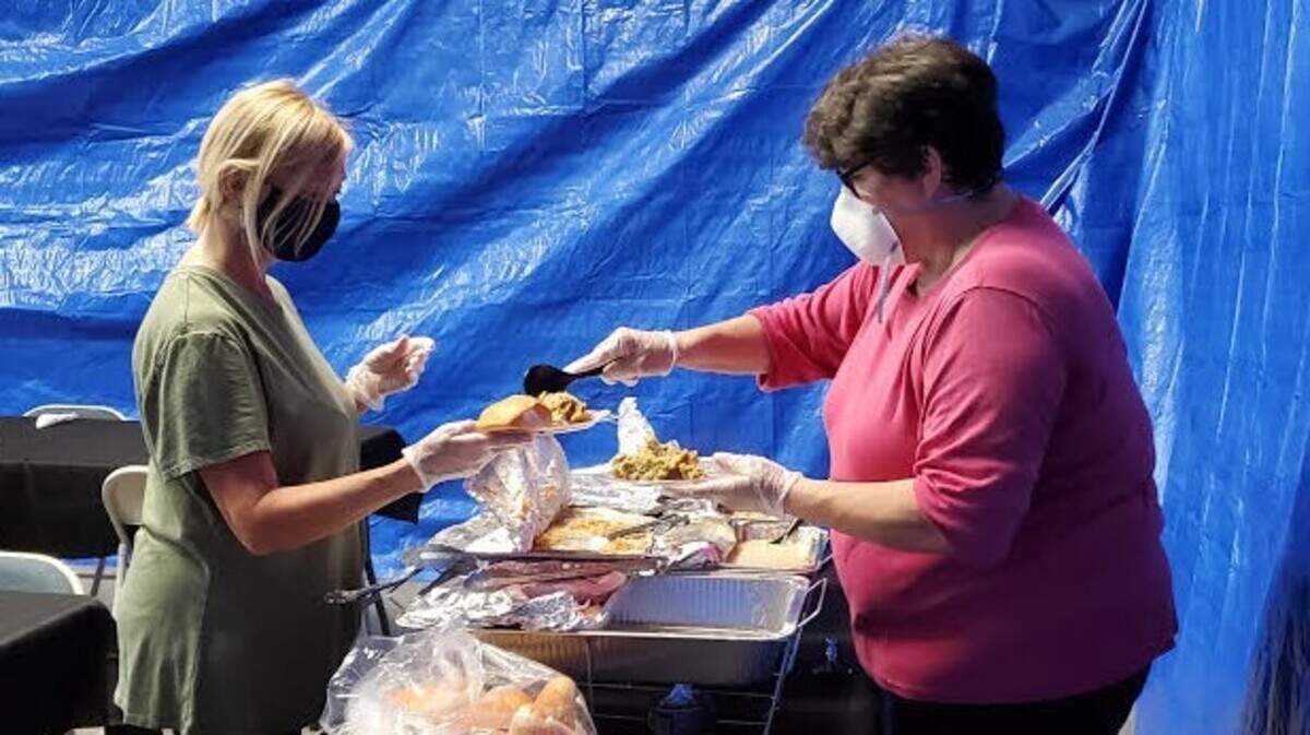 Volunteers at The Shepherd’s Table Stephanie Bourquin (left) and Pam Zmieske (right) dish up a plate for a community Thanksgiving meal.