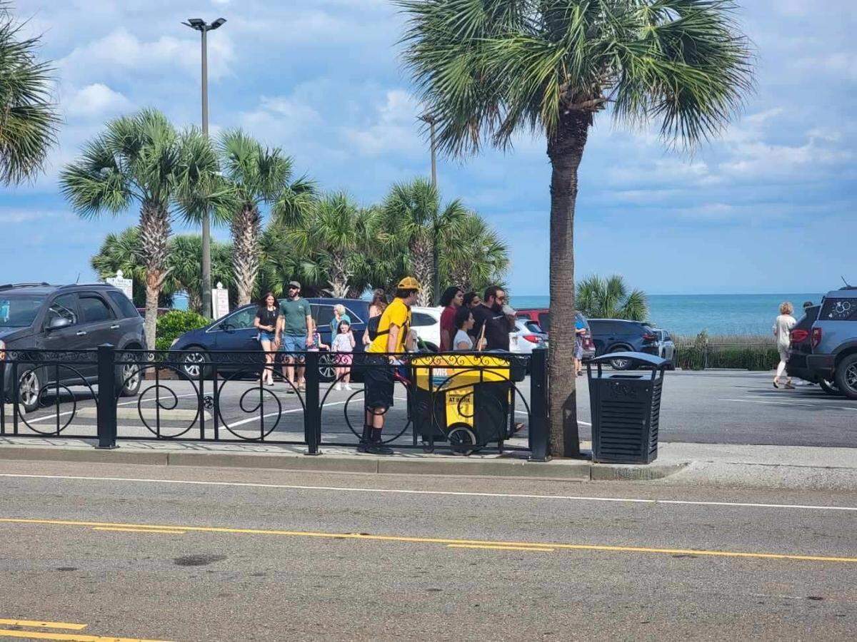 A Gold Cap Ambassador looks for trash and litter to pick up as part of his job keeping downtown Myrtle Beach by the boardwalk clean on Friday, May 30, 2025.
