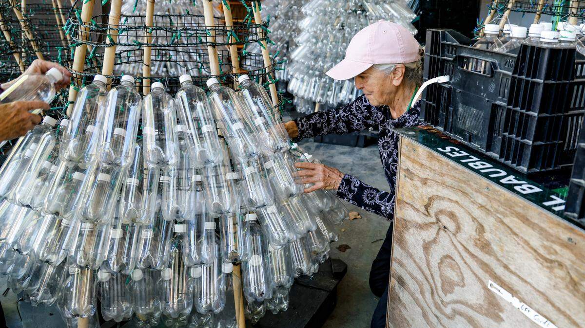 Donna Hand attaches plastic water bottles to trees made out of lights, wire and wood. Workers and volunteers are busily preparing Brookgreen Gardens in Murrells Inlet, S.C. for the Night of a Thousand Candles event starting November 30, 2024. Oct. 31, 2024.