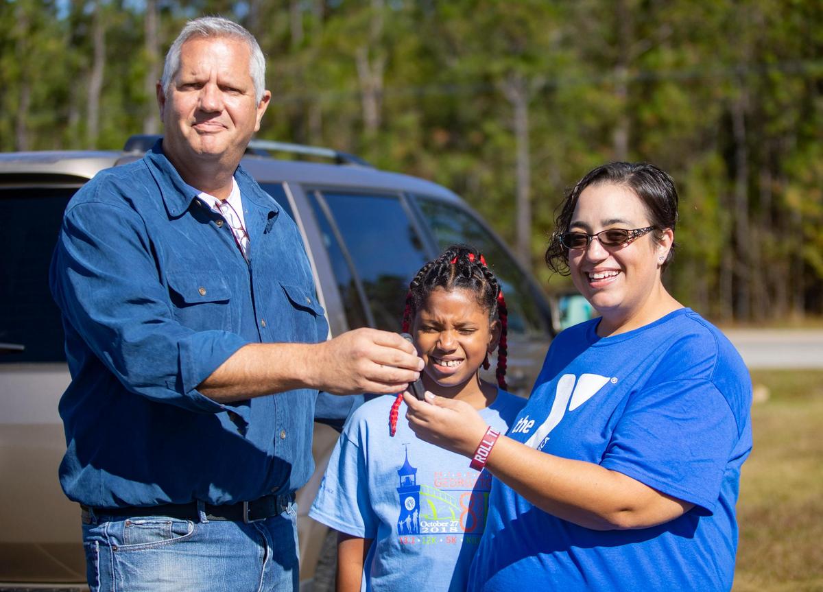YMCA Metro Board member Rodney Long hands over the keys to a gold Honda Pilot Friday to Rachel Pascoe, a member at teh Georgetown YMCA. Pascoe’s boyfriend was in a fatal car accident several weeks ago, leaving Pascoe,  a mother of two, without a car. The family had to rely on others or walking to get home.