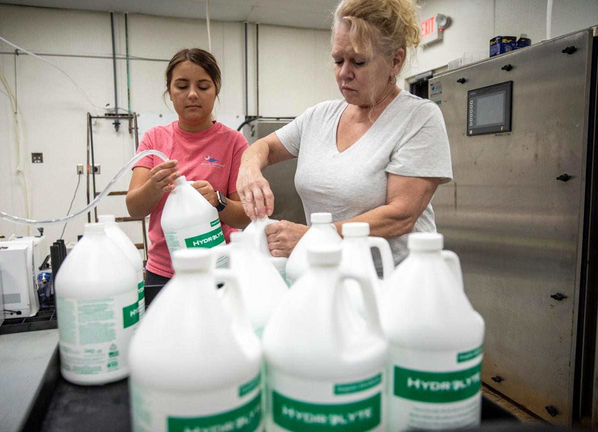Mikayla Logue (left) and Cindi Schoeber, laid off from their work at T-Bonz restaurant, have now been employed by Paradigm Convergence Technologies (P.C.T. Corp.) to package disinfectant. PCT Corp. has shifted their operations from primarily selling equipment used to make fluid solutions, to making the disinfectant solutions themselves and shipping to hospitals around the country. April 13, 2020