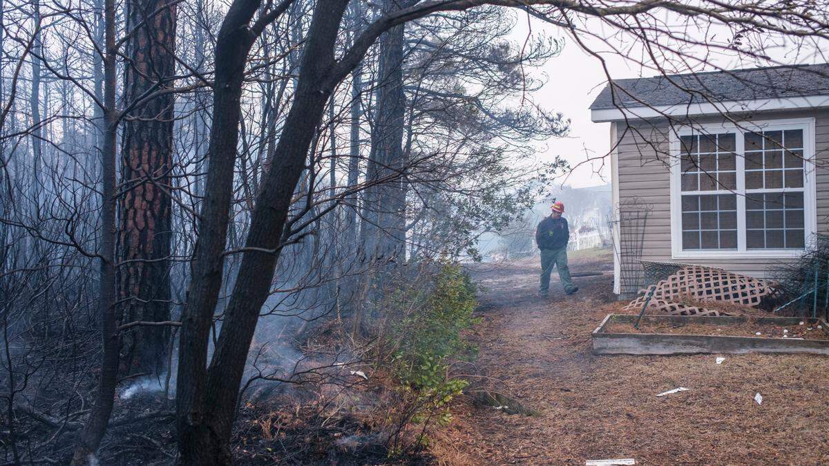 A firefighter looks at damage to homes along Wyandot Ct. Evacuations continued over night for communities in the Carolina Forest area threatened by a forest fire. Firefighters and residents worked to protect their homes from the flames. Sunday, March 2, 2025.