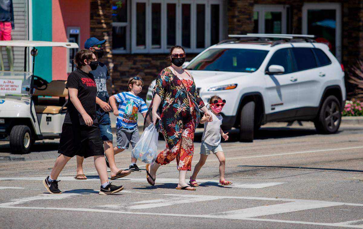 Masked pedestrians cross Main Street Tuesday afternoon in North Myrtle Beach. Coronavirus cases grew by 150 and two virus-related deaths were reported in Horry County Tuesday afternoon, according to state health officials.