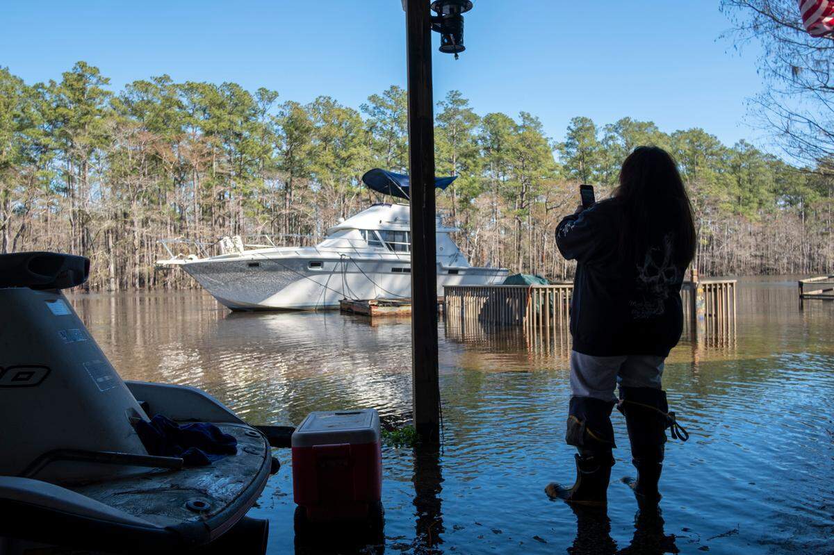 Gina Palliccio takes a picture of the rising water behind her house.