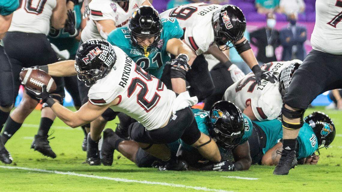 Coastal Carolina running back Christian Malloy (25) dives into the end zone for a touchdown while Northern Illinois cornerback Emmanuel Harris (21) dives on him during the Cure Bowl NCAA college football game in Orlando, Fla., Friday, Dec. 17, 2021. (Willie J. Allen Jr./Orlando Sentinel via AP)