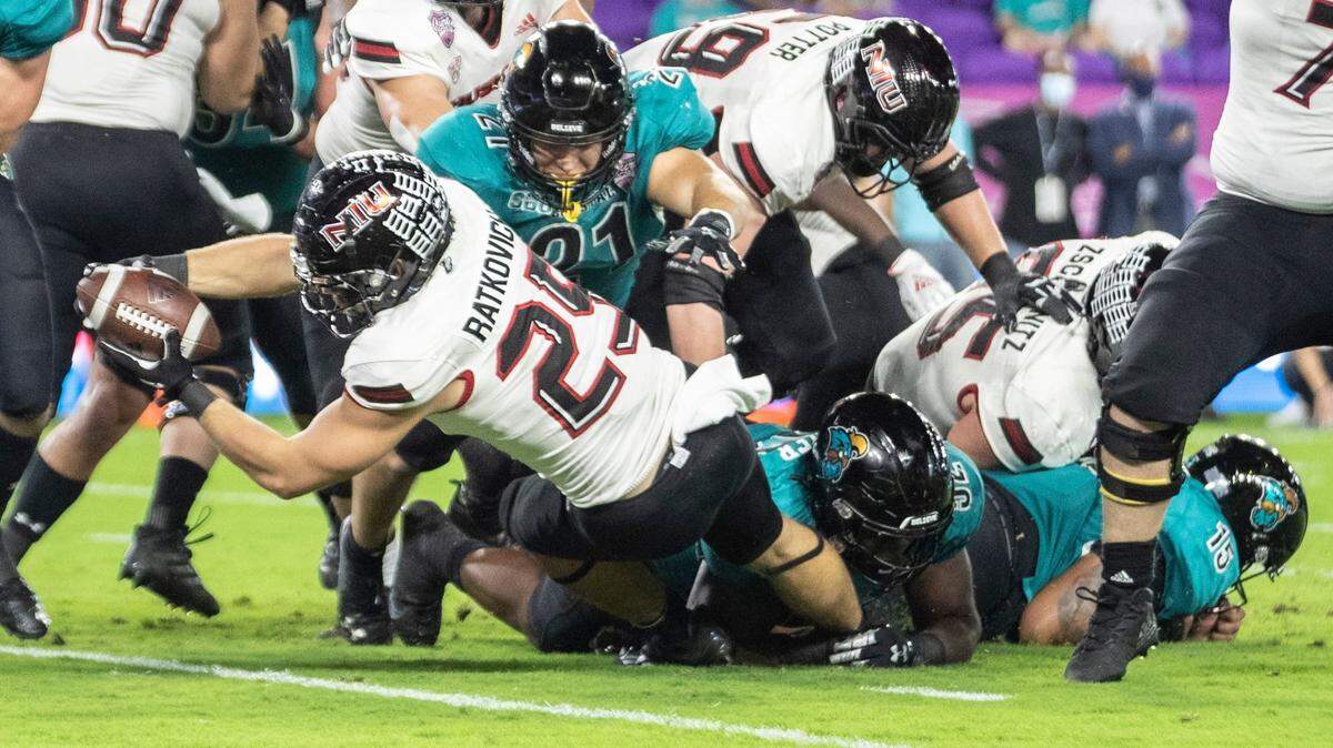 Coastal Carolina running back Christian Malloy (25) dives into the end zone for a touchdown while Northern Illinois cornerback Emmanuel Harris (21) dives on him during the Cure Bowl NCAA college football game in Orlando, Fla., Friday, Dec. 17, 2021. (Willie J. Allen Jr./Orlando Sentinel via AP)