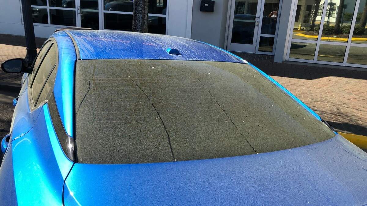 An image of yellow tree pollen coating the windshield of a car.