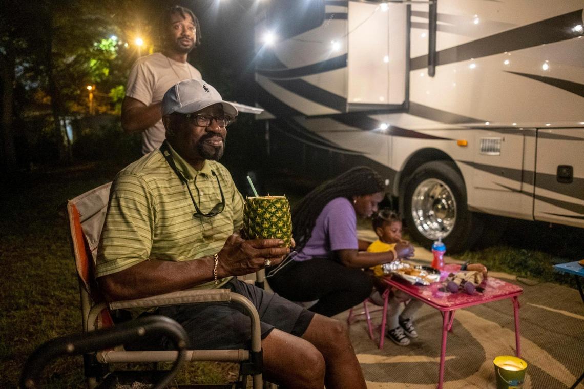 Dr. Stewart Darby, a Columbia, S.C. physician enjoys a pineapple drink while camping with his family on his empty lot in Atlantic Beach and watching the bikers on Friday night.