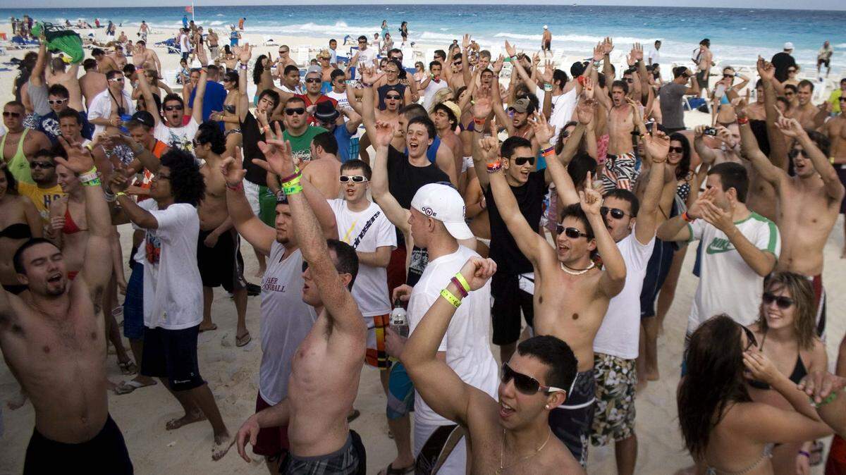 Students on spring break cheer Monday at the beach in Cancun.