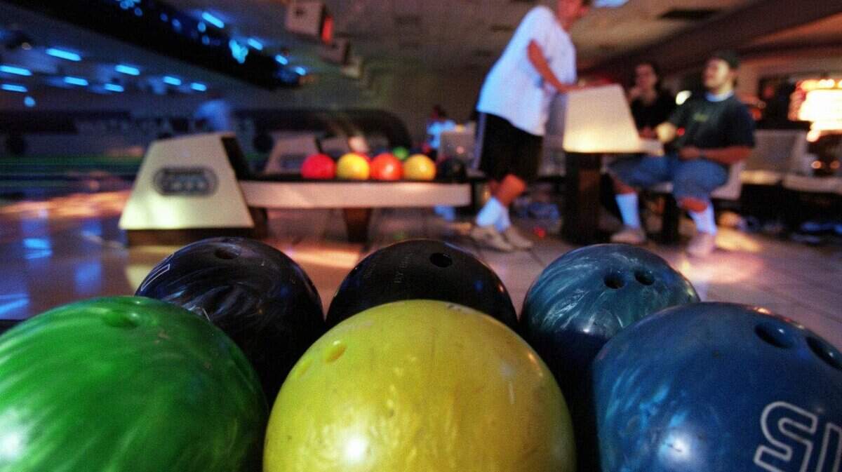 KRT LIFESTYLE STORY SLUGGED: COSMIC KRT PHOTOGRAPH BY JON FREILICH/DALLAS MORNING NEWS (KRT6-August 11) Brightly colored bowling balls await use during Cosmic Bowling night at Brunswick Watauga Lanes as Brandon Casey, 17, of Colleyville, Texas, chats with friends. Brunswick, a chain of 122 bowling alleys, introduced cosmic bowling about three years ago as a way to attract younger bowlers. (DA) PL KD 1998 (Horiz) NO MAGS, NO SALES