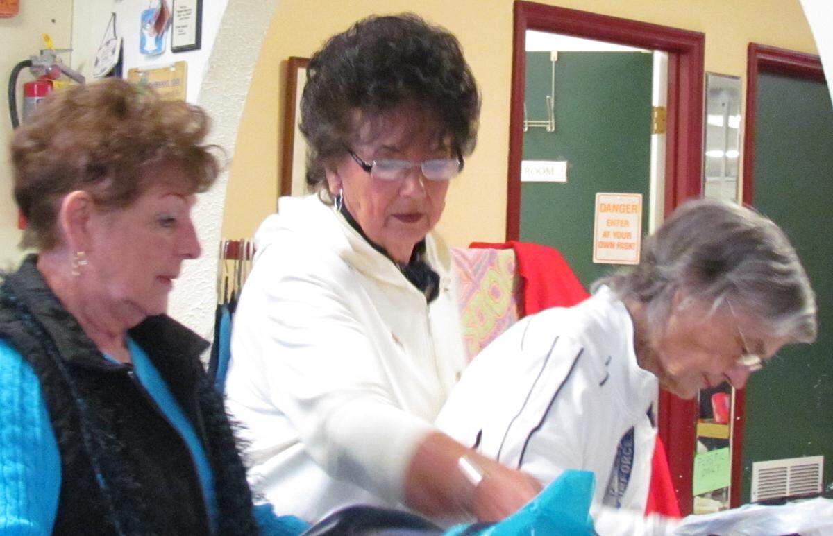 Volunteers Joy Barnard (left), Linda Owens and Mary Catherine Hardee search for a backpack a customer requested at Associated Charities Inc.