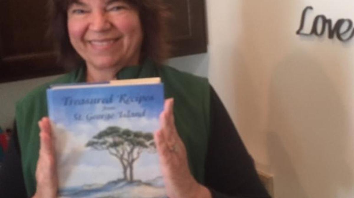 Sharon Bridges stands with her favorite cookbook “Treasured Recipes from St. George Island.”
