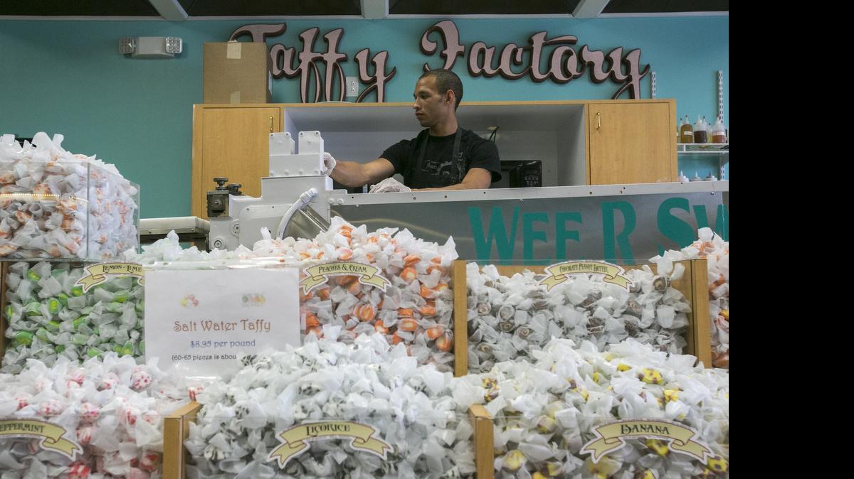 
Chris Williams runs taffy through a more than 100-year-old, small candy-wrapping machine at Wee-R-Sweets in North Myrtle Beach where saltwater taffy, chocolates and ice cream are made on-site. June is National Candy Month. 
