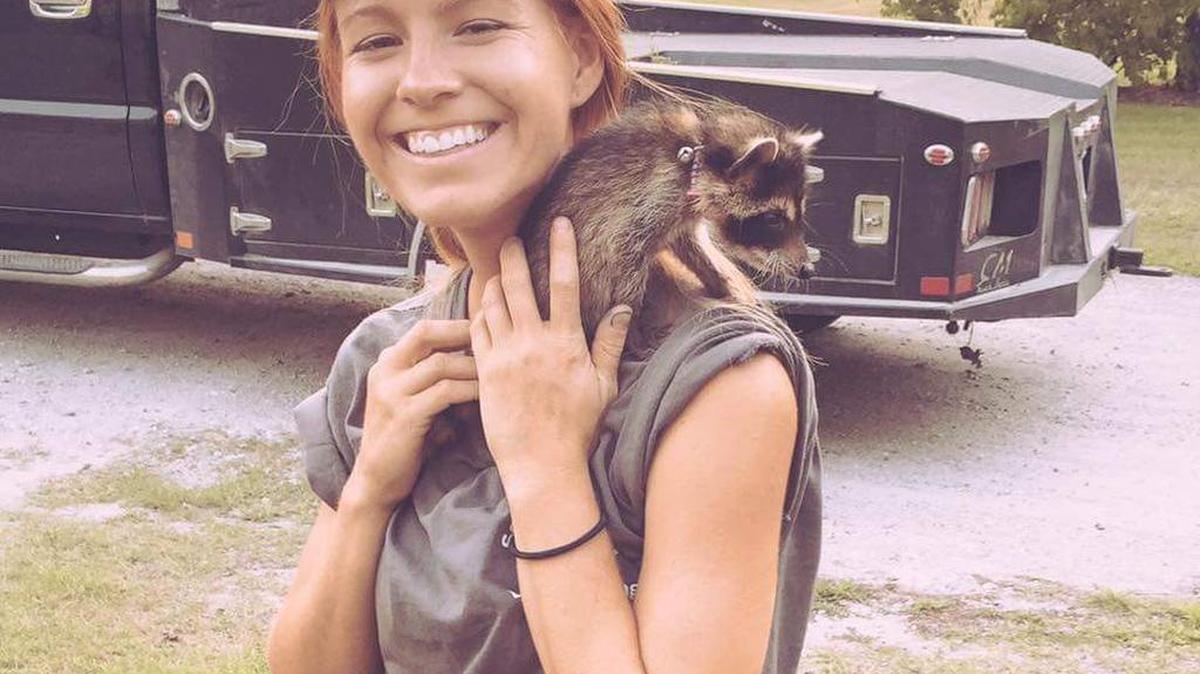 Miracle Lewis with a raccoon.