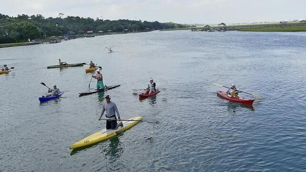 Kayaks and standup paddle boards race along Pawleys Creek.