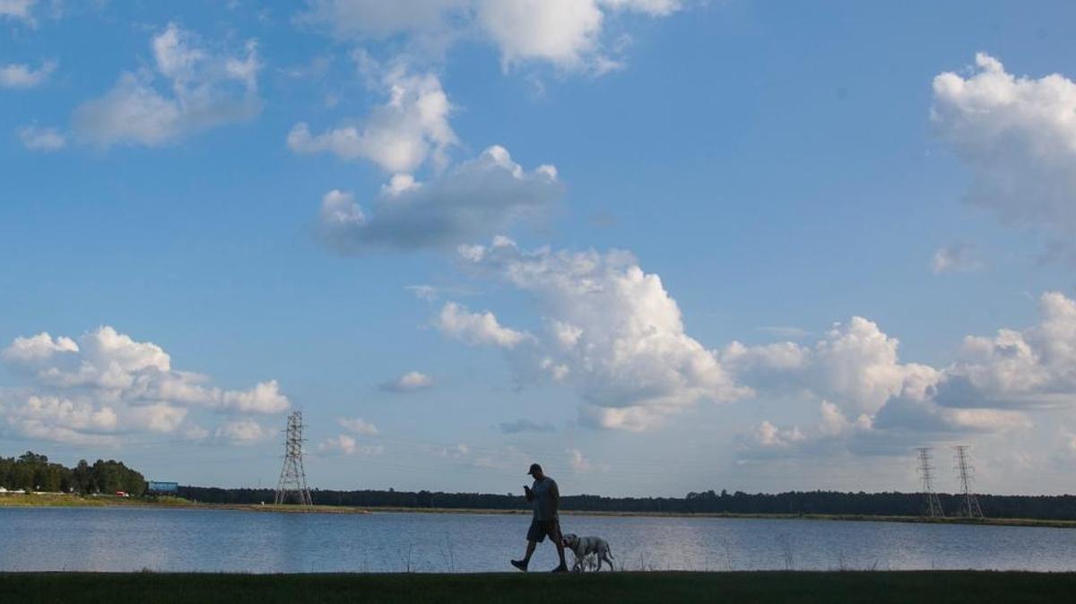 A Conway resident walks his dog around Lake Busbee on Monday evening. September 18, 2017.