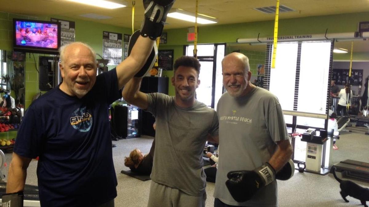 Tom Gantt of Calabash, N.C. (left), who has Parkinson’s disease, boxes for exercise with trainer Amos Collins, wrestling coach at North Myrtle Beach High School in Leland, N.C., and personal friend Whit Brown.