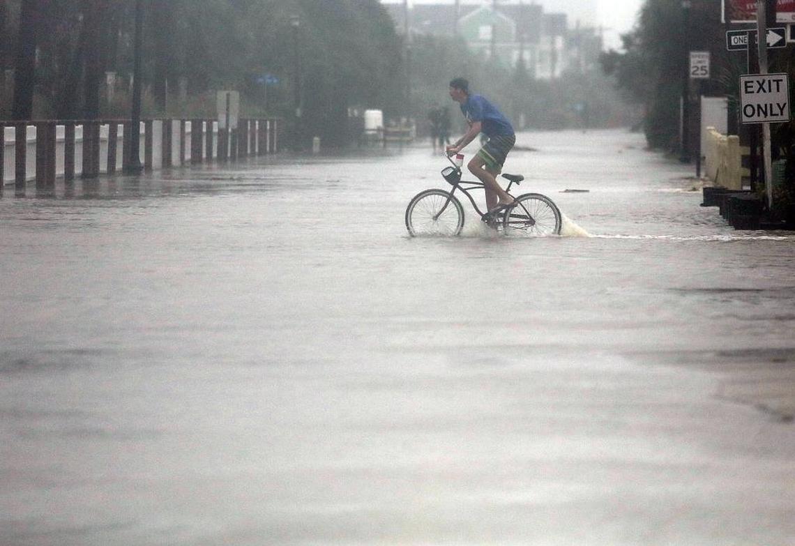 A man rode through the flooded streets in Surfside Beach on Saturday, Oct. 8, 2016, as Hurricane Matthew traveled north.