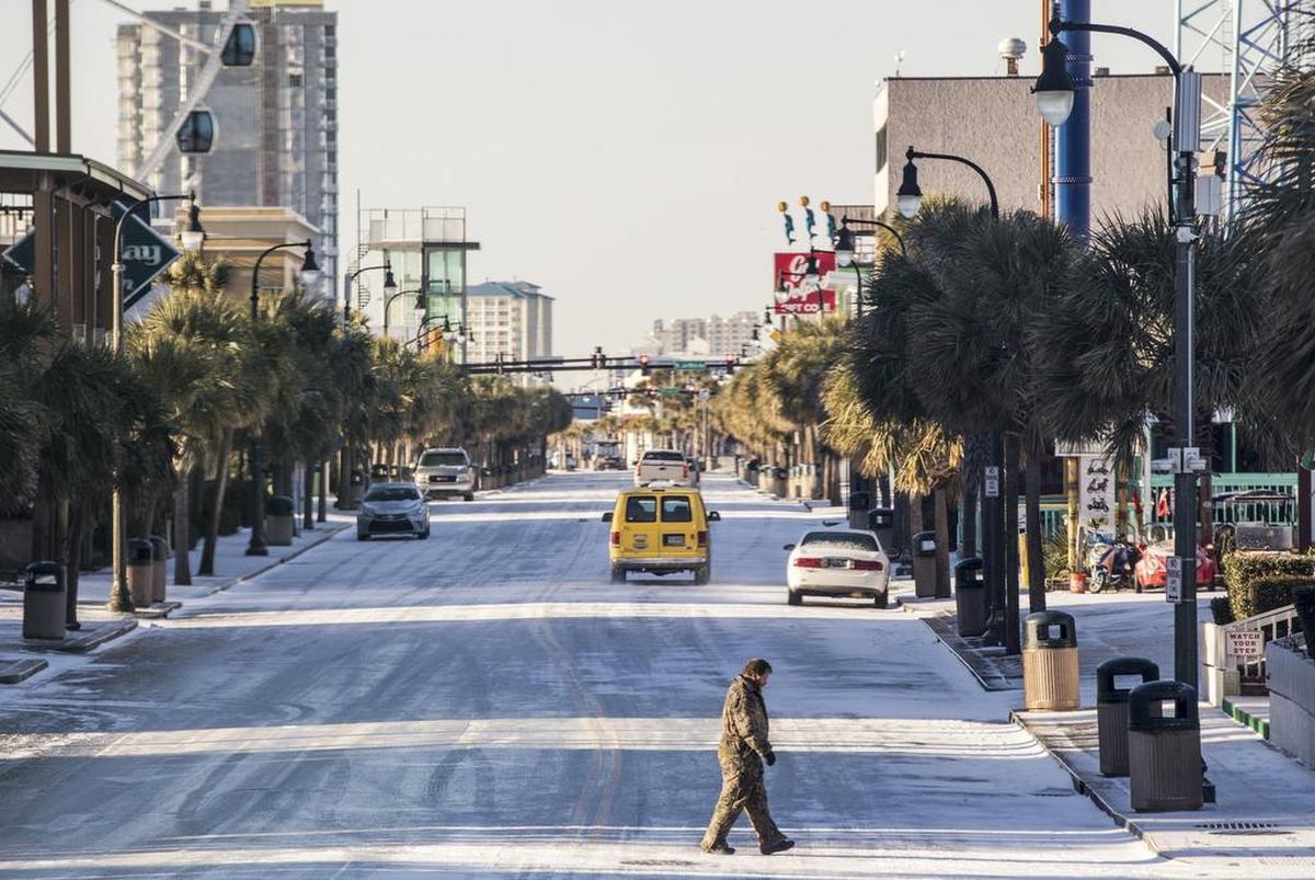 A pedestrian carefully crosses Ocean Boulevard in Myrtle Beach on Thursday morning. The Grand Strand missed out on the heaviest snows from Winter Storm Grayson, but area roads were solid sheets of ice on Thursday morning Thursday. Jan. 4, 2018.