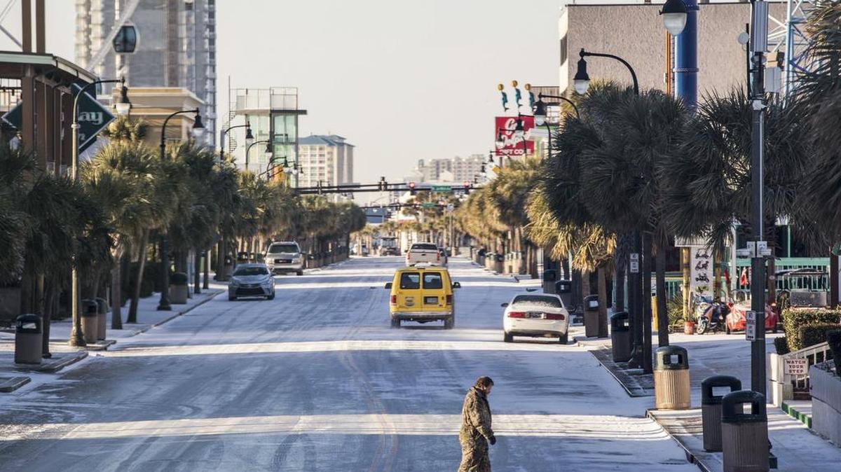 A pedestrian carefully crosses Ocean Boulevard in Myrtle Beach in 2018. Myrtle received a dusting of snow this weekend, and temperatures are expected to plunge into the low 20s Saturday night and Sunday morning.