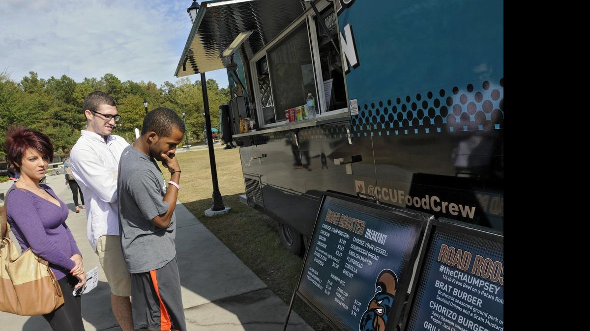 
Alyssa Bowen, Nick Maglionico and Tony Gibbs look over the menu at the Road Rooster food wagon on Prince Lawn on the Coastal Carolina University campus.
