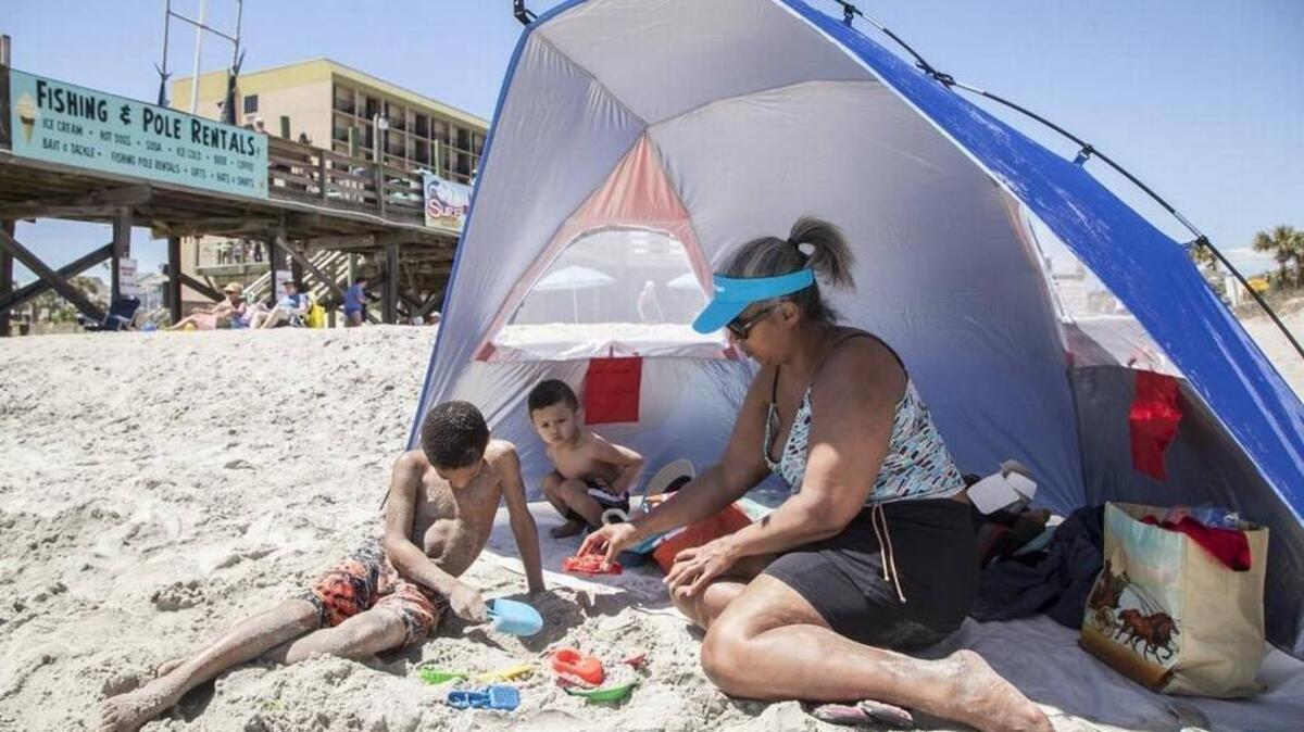Ida Diaz with sons Jeremiah and Jared of Mary, Conn, lounge under the shade of a tent on Surfside Beach on Tuesday, April 11, 2017. The town of Surfside is considering an ordinance that would ban tents on the beach, though smaller “baby tents” would still be allowed.