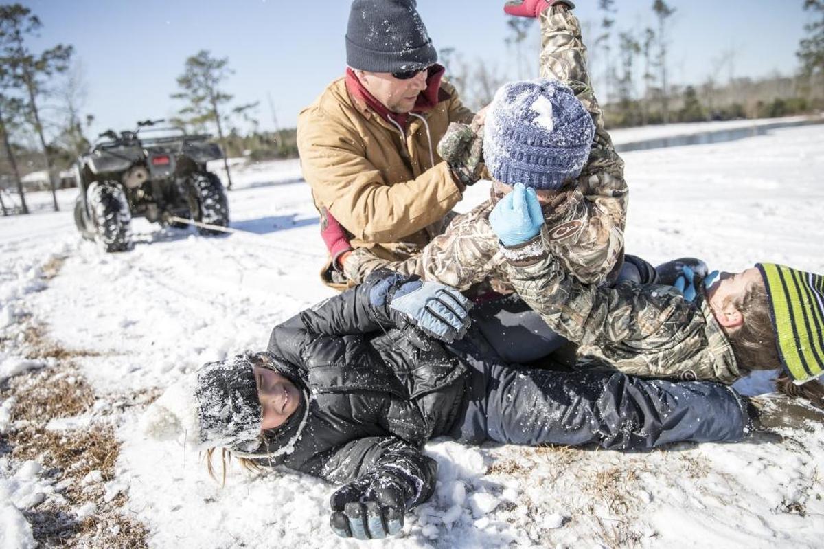 Chuck Harrelson wrestles with his friends children in the snow at the Harrelson family farm outside Aynor on Thursday. While much of the Grand Strand missed the heaviest snowfall from Winter Storm Grayson, residents of Aynor woke up to over three inches of snow on Thursday. Jan. 4, 2018.