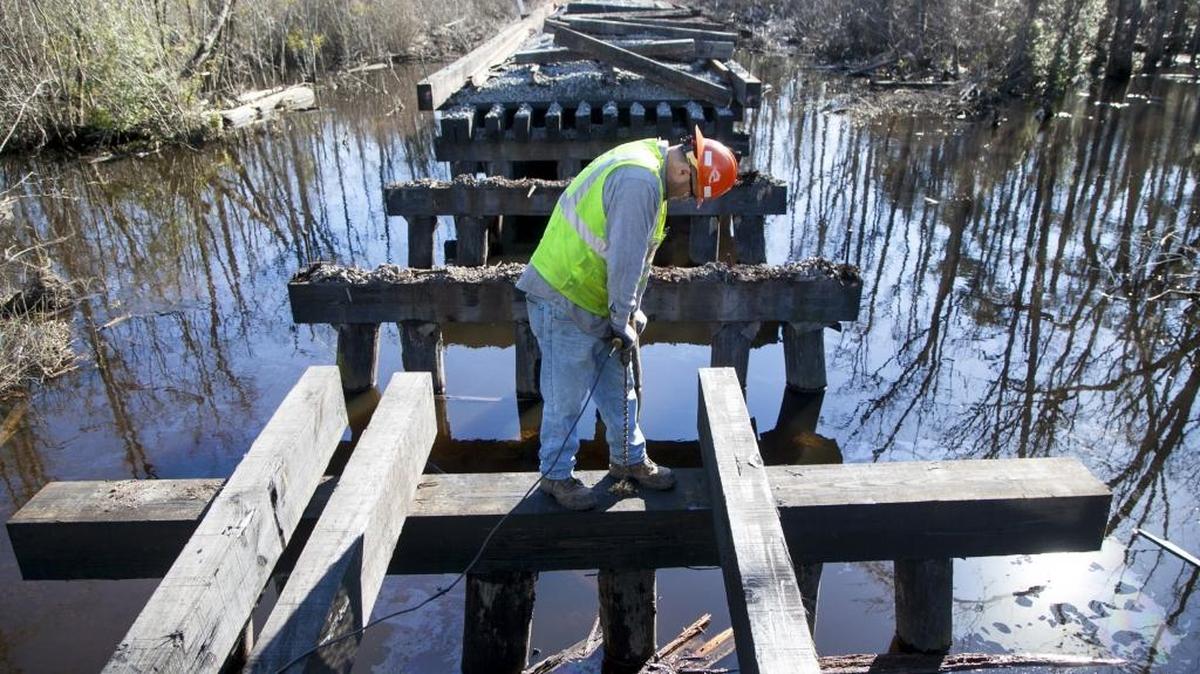 R.J. Corman railroad worker Merrell Taulbee drills holes for replacement stringers to repair a bridge over Bug Swamp near Loris on Friday. The train operator expects repairs to take a least a few more weeks and hopes to be operating by mid-March.