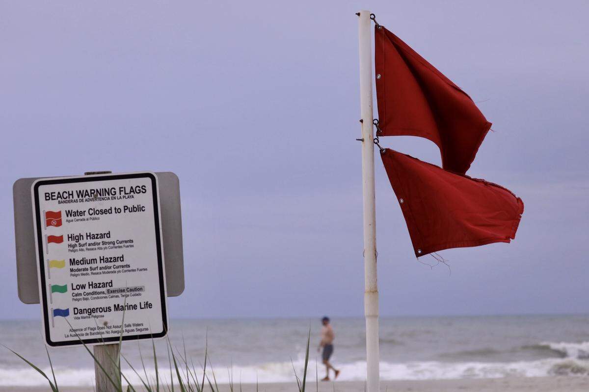 A lone surf watcher strolls along the beach Monday morning ahead of Hurricane Isaias.