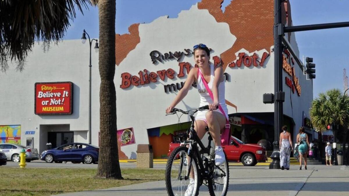 
A girl rides her bicycle on the sidewalk alongside Ocean Boulevard.
