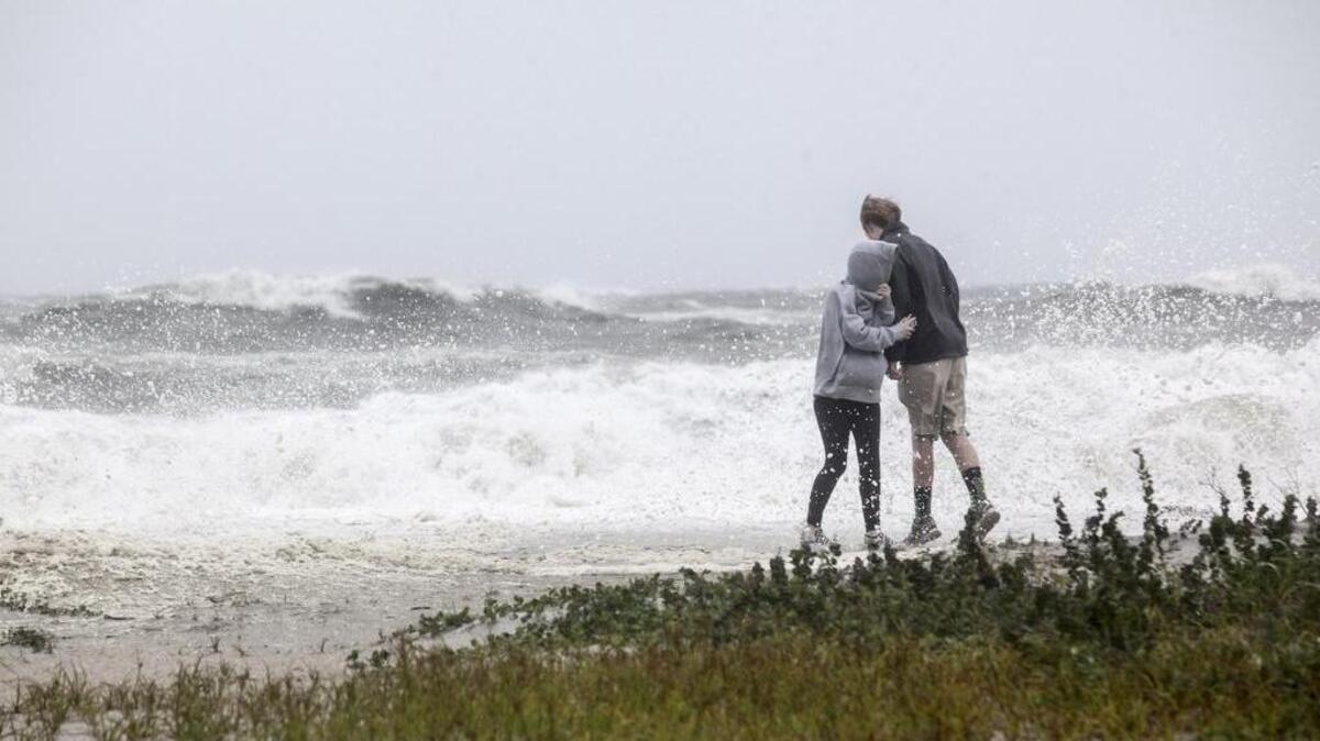 Alycia Carter ducks behind Trenton Friedman as waves spray over the dunes at Garden City Beach. The remnants of Hurricane Irma begins to batter Garden City Beach on Monday morning. Sept. 11, 2017