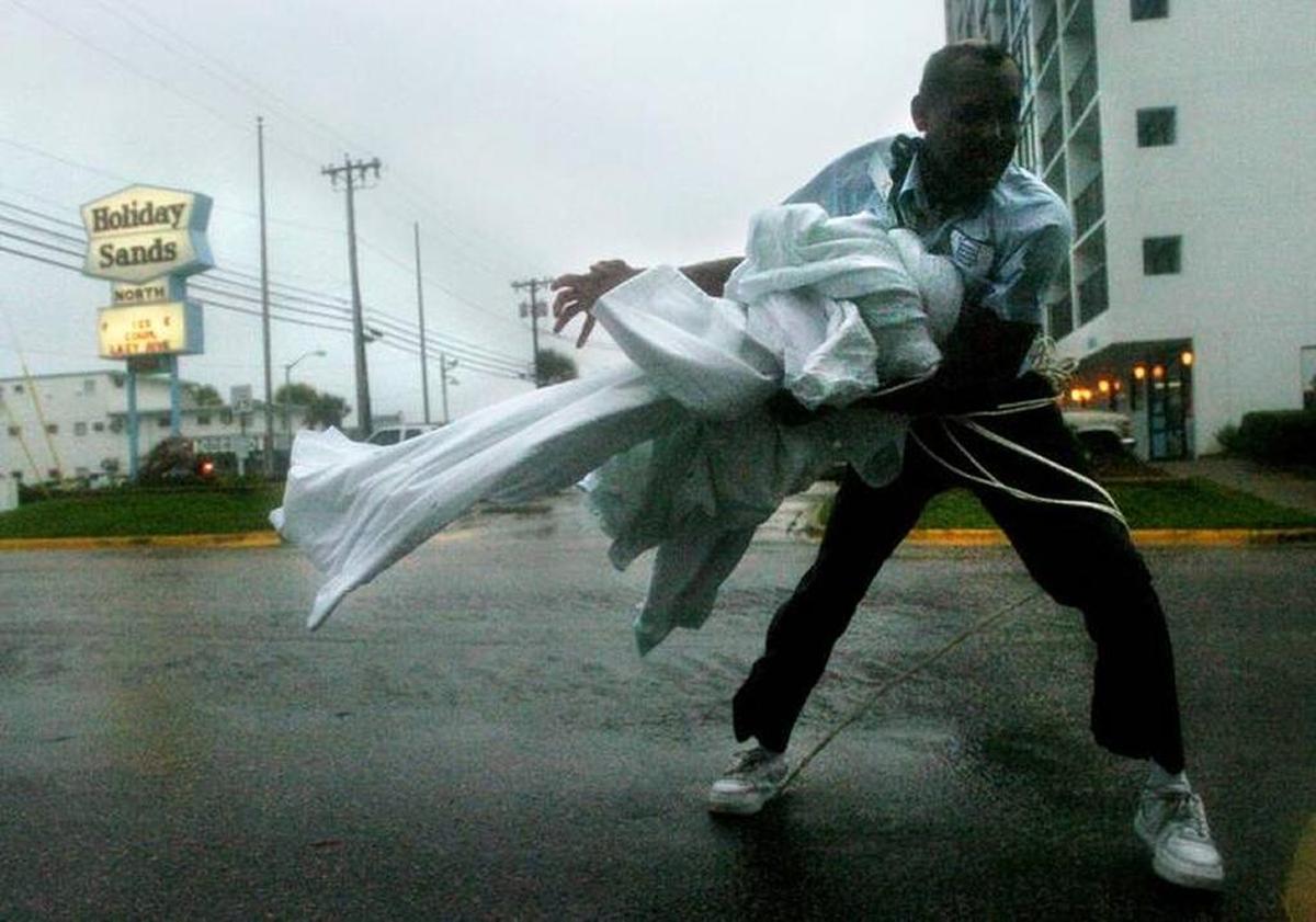James Thomas, a maintenance man for the Holiday Sands North hotel off of Ocean Blvd., picks up sheets after they were blown awayas Hurricane Charley came through Myrtle Beach in 2004.