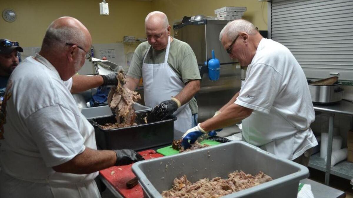 
Pictured with skills akin to a surgeon are Men’s Auxiliary members (from left) Don Thompson, Chaz Rowe and Greg Tucker pulling the pork after its fully cooked. 
