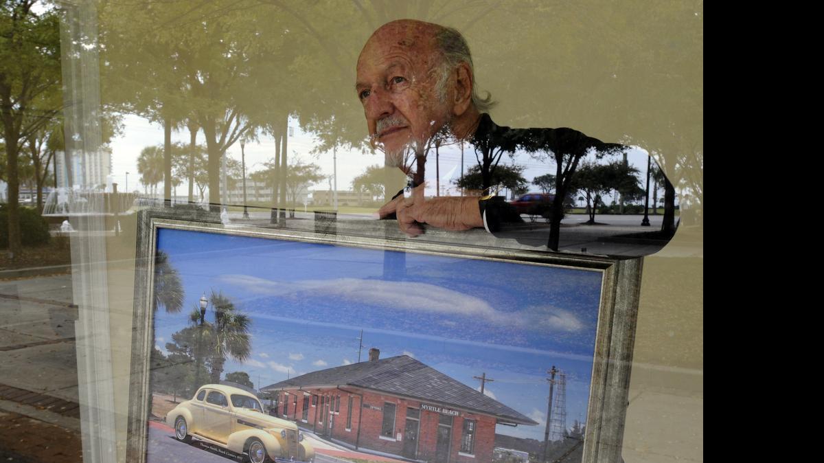 
Long-time Myrtle Beach photographer Jack Thompson looks out a window at 503 Ninth Ave. N., across Nance Plaza at the old Pavilion site, reflected in the glass, where he once had a studio. All of Thompson’s studios have been within a short distance of this location, “I just can’t get away from this corner,” he said.
