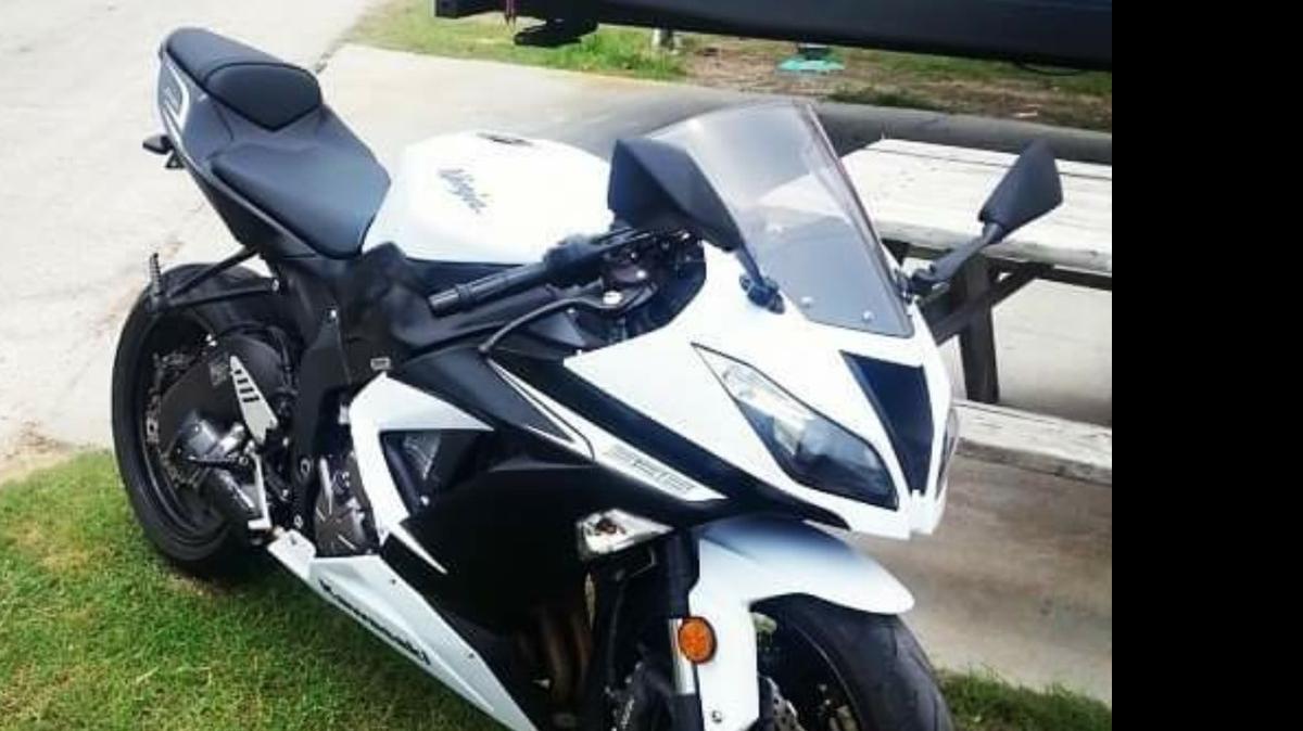 
The motorcycle is a 2013 Kawasaki Ninja ZX6R model, black and white in color with custom ‘two brothers racing’ exhaust and a ‘gremlin bell’ near the foot peg on the right side.
