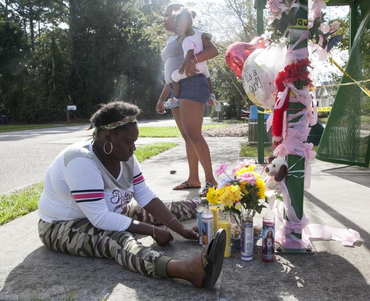 Amanda Alston, along with Rasheeda Stephens with 1-year-old Yanna Bellamy, visit a makeshift memorial for Jadasia Monique Myers at Futrell Park near the sight where the 22-year-old pregnant mother was shot and killed on Sunday. Myers' child also died during delivery.