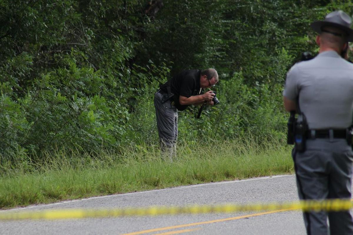 An investigator takes pictures in a ditch along the Peachtree Road, where a body was found Saturday morning. The South Carolina Highway Patrol is investigating.