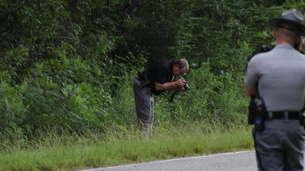An investigator takes pictures in a ditch along the Peachtree Road, where a body was found Saturday morning. The South Carolina Highway Patrol is investigating.