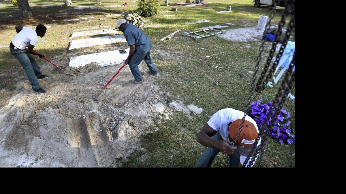 
John Guiles (center) and his crew prepare the grave of Quentin Reeves. They carefully fill in the open spaces with shovels of dirt, making sure the marker is centered and level. Guiles has been digging graves since 1986 and has buried two of the last three men killed in the Longs area since March 22. On April 25, he leans against the red handle of his shovel shaking his head as he talks about the death of the North Myrtle Beach High School senior. Reeves was shot on prom night at The Party Shop off S.C. 90.  In the area, there have been multiple shootings leaving three men dead at three different locations since March 22.
